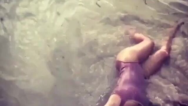 Salma Hayek laying in water on the beach